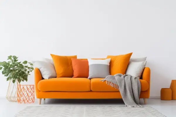 Divano arancione acceso, un'ispirazione per come scegliere il colore del divano. Cuscini colorati e coperta grigia completano l'arredo.