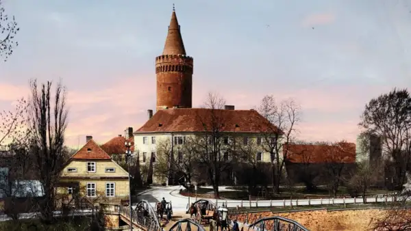 Opole stare miasto: zamek z wieżą, mosty, dorożki i kamienne domy pod różowym niebem.