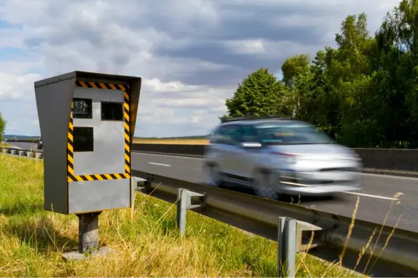 Un appareil de contrôle homologué en mouvement, un radar de vitesse sur le bord de la route, observe une voiture passer à toute allure.