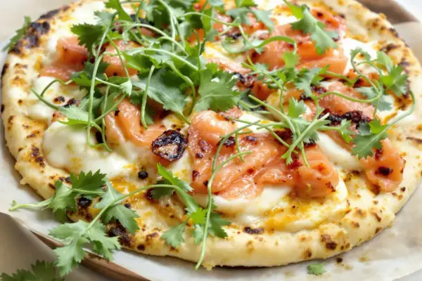 Pizza saumon avec fromage fondant, garnie de coriandre fraîche et d'une touche de piment. Un délice visuel et gustatif.