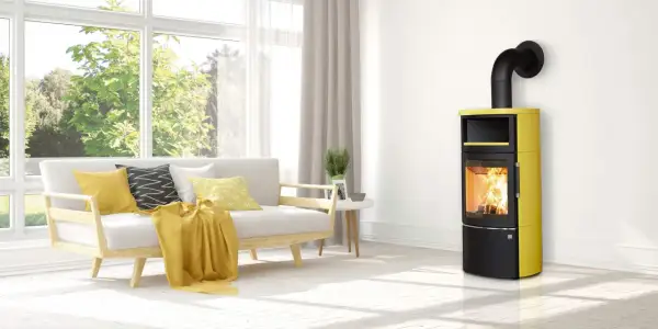 Moderner Kaminofen in Gelb und Schwarz mit brennendem Holz. Der Ofenrohr Abstand zum Holz ist sicher eingehalten.