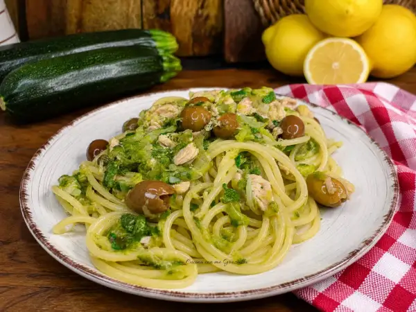Un piatto invitante di pasta con zucchine e tonno, condita con olive e un tocco di limone.