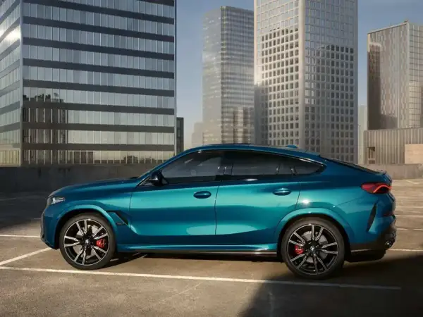 Błękitne x6 BMW lśni na tle nowoczesnych wieżowców.