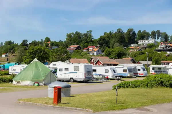 Husvagnar och husbilar står uppradade på en campingplats i Norrköping. En grön kupoltält står i förgrunden.