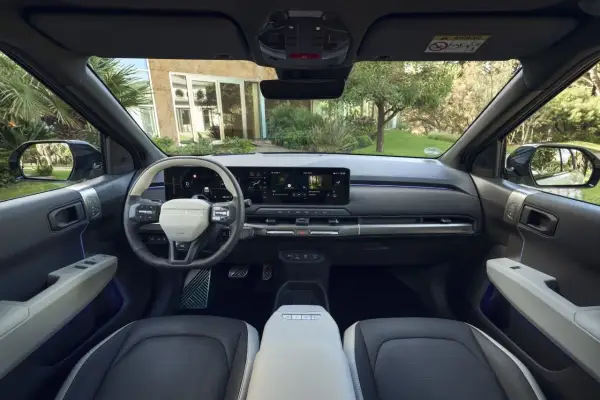 Interior del Kia EV3 con pantalla táctil panorámica, volante moderno y asientos de dos tonos.
