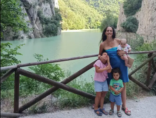 Famiglia felice nella Gola del Furlo, con un lago turchese e rocce imponenti.