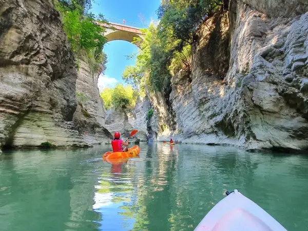 Kayak tra imponenti pareti rocciose, simili a **marmitte dei giganti**, sotto un antico ponte.