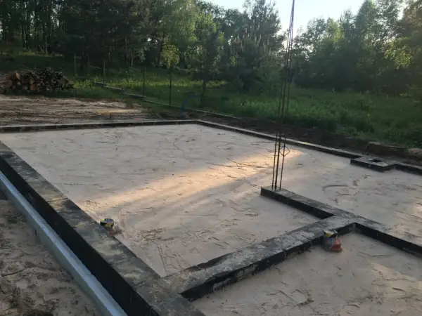 Płyta fundamentowa przygotowana do zimowania. Jak zabezpieczyć płytę fundamentową na zimę? Widać zbrojenie i piasek.