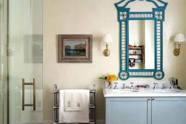 Elegante baño sin azulejos, con lavabo doble, espejo azul y cuadro de paisaje.