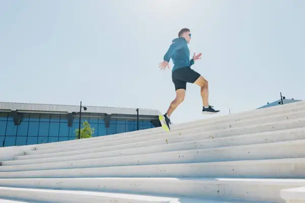 Un homme court sur des escaliers extérieurs. Est-ce que courir fait maigrir ? Oui, l'effort physique comme celui-ci aide à brûler des calories.