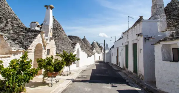 Un vicolo tra i trulli, con i loro tetti conici in pietra, mostra cosa sono i trulli, un'architettura unica della Puglia.