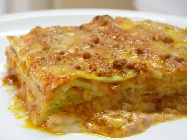 Une part de lasagne généreuse, aux couches de pâtes, sauce bolognaise et béchamel, évoquant la richesse de la lasagne origine.