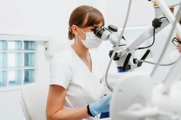 Dentystka bada zęby pod mikroskopem. Nieleczona próchnica może prowadzić do poważnych problemów.