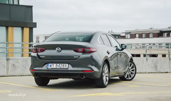 Szary sedan Mazda 3 na parkingu. Sprawdzamy mazda 3 spalanie i wrażenia z jazdy.
