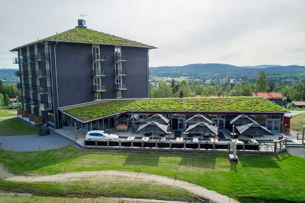 Modernt B&B Järvsö med gröna tak och utsikt över landskapet. Uteservering med parasoller.