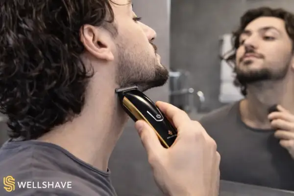 Un homme ajuste sa barbe 3mm avec une tondeuse dorée et noire devant un miroir.