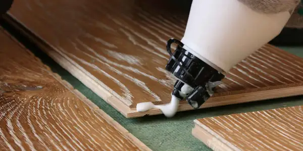 Application de colle sur du bois stratifié. Pour savoir comment enlever de la colle sur du bois stratifié, il faut agir vite.