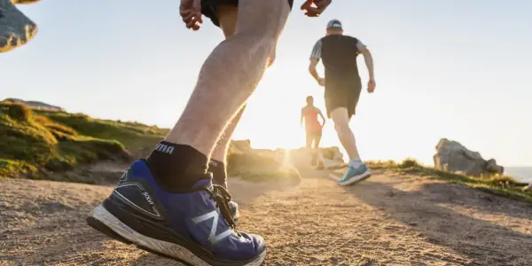 Coureurs sur un sentier de trail en Bretagne, profitant du soleil couchant sur la côte.
