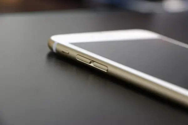 Złoty iPhone leży na ciemnym blacie. Wiesz, jak znaleźć iPhone, gdy go zgubisz?