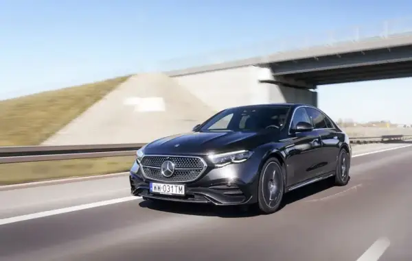 Elegancki, czarny Mercedes E220d pędzi autostradą pod mostem.