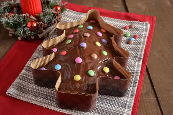Dolce a forma di albero di Natale ricoperto di glassa al cioccolato e decorato con caramelle colorate.