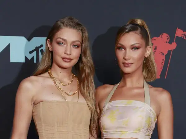 Alana Hadid y su hermana Bella posan juntas en la alfombra roja, luciendo atuendos elegantes y maquillaje impecable.