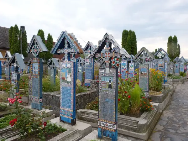Kolorowe nagrobki Wesołego Cmentarza w Rumunii, ozdobione malowidłami i rzeźbieniami, tworzą unikalny krajobraz.