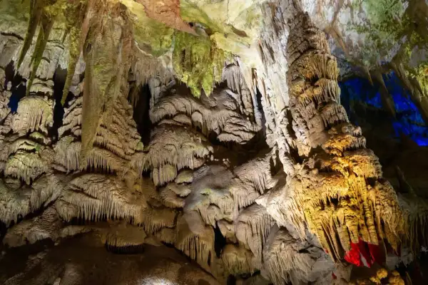 Wnętrze jaskini Prometeusza, pełne stalaktytów i stalagmitów, oświetlone ciepłym, żółtym światłem i niebieskimi akcentami.