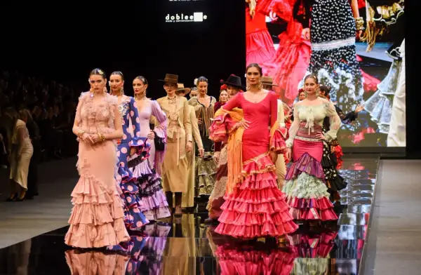 Modelos desfilan en la **pasarela SIMOF** con trajes de flamenca vibrantes y volantes.