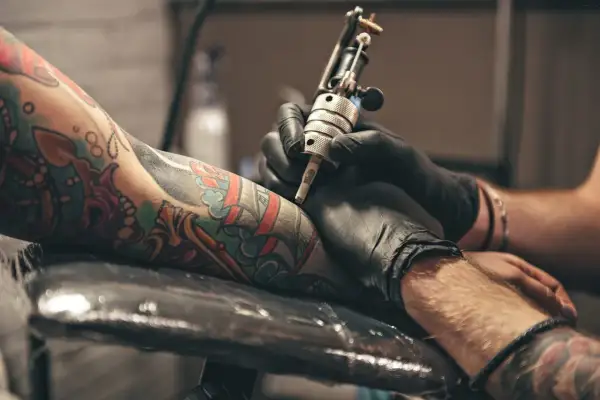 Un artista de **london tattoo** trabaja en un brazo con un diseño colorido.