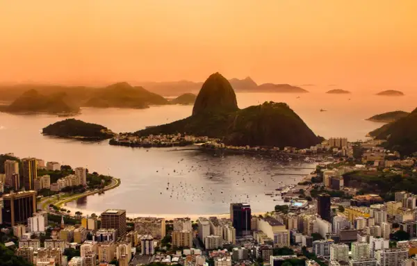 Widok na Rio de Janeiro o zachodzie słońca. W tle góry i zatoka z łodziami. Marzenie o podróży do Brazylii i szczepienia na wyjazd.