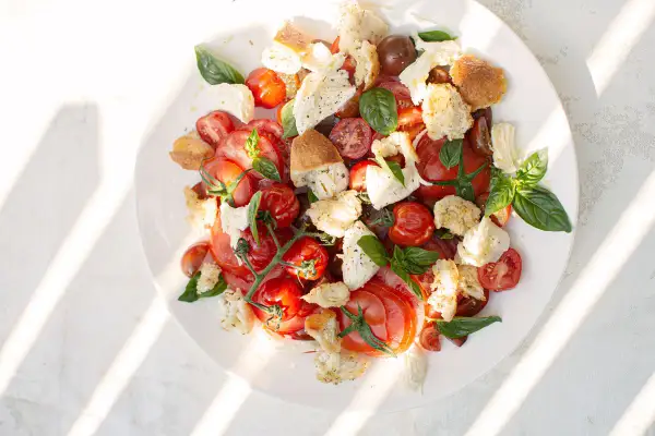 Tomate Mozzarella Salat mit geröstetem Brot und Basilikum, ein sommerlicher Genuss.