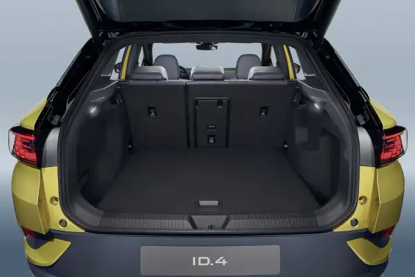 Vue du coffre ouvert d'une Volkswagen ID.4 jaune. Le volume du coffre est spacieux, prêt à accueillir vos bagages pour un long voyage.