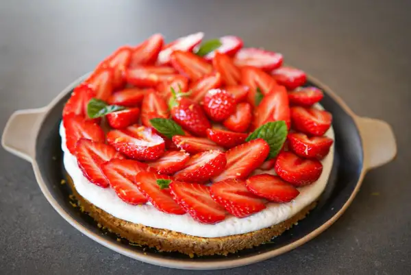 Tarte aux fraises mascarpone, une gourmandise estivale recouverte de fruits rouges frais et de feuilles de menthe.
