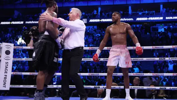 A referee separates two boxers in a ring. Interesting boxing facts: the referee's job is crucial for fighter safety.