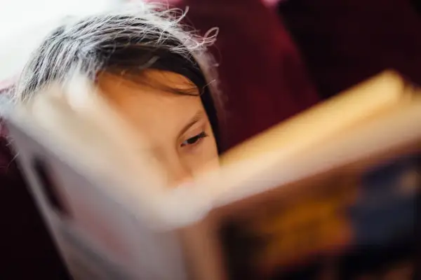 Niña concentrada en la lectoescritura, página de libro abierto.