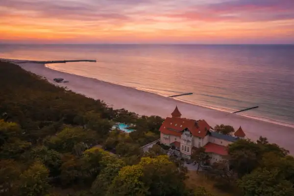 Zachód słońca nad Bałtykiem, idealne miejsce, gdzie na wakacje w Polsce. Piękna plaża, las i zabytkowy budynek z basenem.