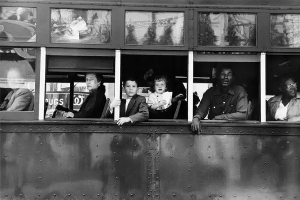 Dzieci i dorośli patrzą z okien tramwaju, uchwyceni okiem Roberta Franka.
