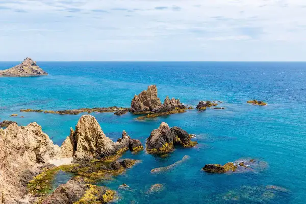 Formaciones rocosas emergen del mar turquesa, como un arrecife del dedo señalando el horizonte.