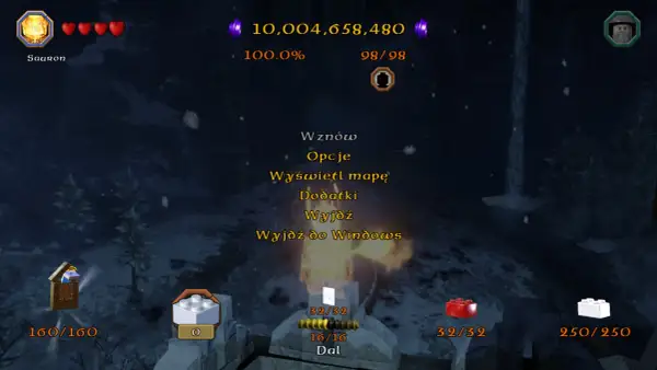 Menu gry Lego Hobbit. Widać postać Saurona, serduszka życia, punkty, procent ukończenia, a także opcje takie jak "Dodatki" i "Wznow", które mogą być powiązane z lego hobbit kody.