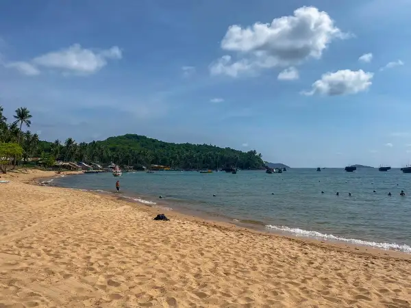 Piękna plaża z palmami, łodzie na turkusowym morzu i zielona wyspa. To idealne miejsce na odkrywanie Wietnamu na własną rękę.