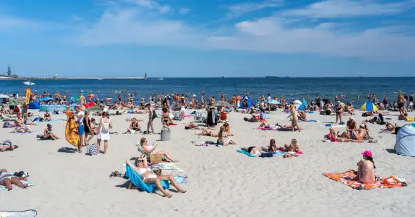 Tłumy ludzi na plaży, opalanie i kąpiel w morzu. Zastanawiasz się, ile kosztuje nocleg nad morzem w sezonie?