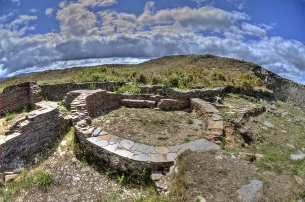 Ruinas circulares de piedra del castro de Formigueiros, con muros bajos y un patio central.