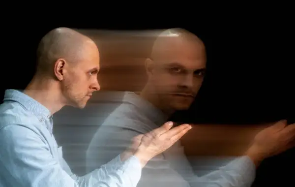 Uomo calvo con effetto mosso, sembra diviso tra due stati, un'immagine che evoca un disturbo del controllo.