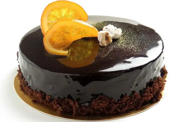 Torta lucida al cioccolato con fette d'arancia candita e nocciole. Un delizioso mousse cioccolato e arancia che invita a un assaggio.