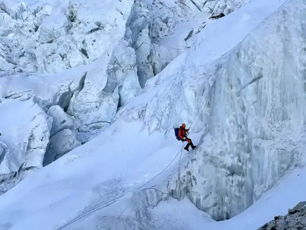 Bergsteiger seilt sich im Khumbu Icefall ab, umgeben von zerklüftetem Eis und tiefen Gletscherspalten.