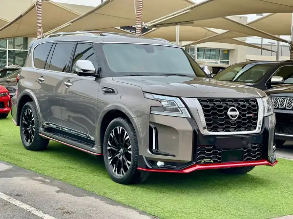Szary Nissan Patrol 2025 Nismo z czerwonymi akcentami, prezentujący się na zielonej trawie.