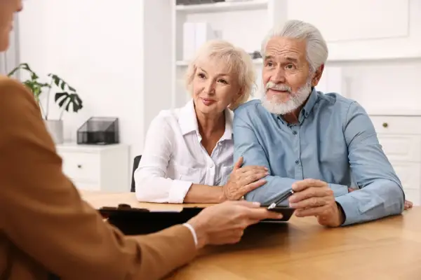 Un couple âgé discute d'une procuration pour leur compte bancaire avec un conseiller.