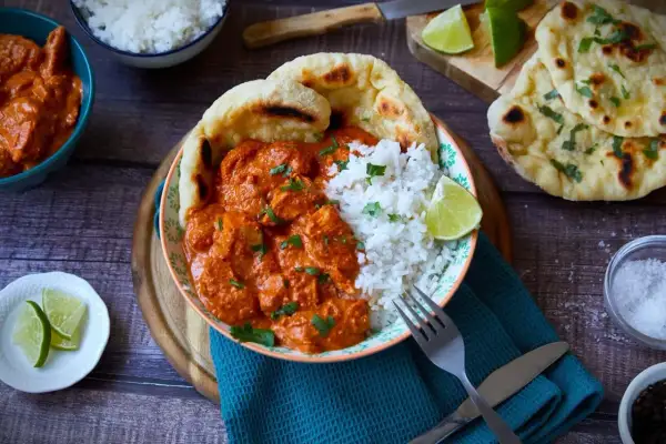 Ein köstliches Butter Chicken Rezept mit Reis, Naan und Limettenspalten. Perfekt für ein authentisches indisches Essen.