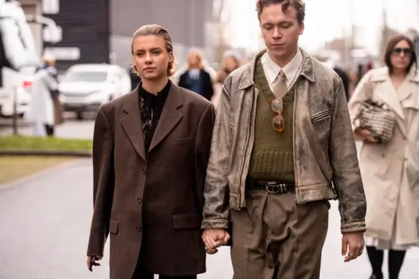 Ein Paar im **Copenhagen Style** geht Händchen haltend. Sie trägt einen braunen Oversize-Blazer, er eine Lederjacke über einem Strickpullover.